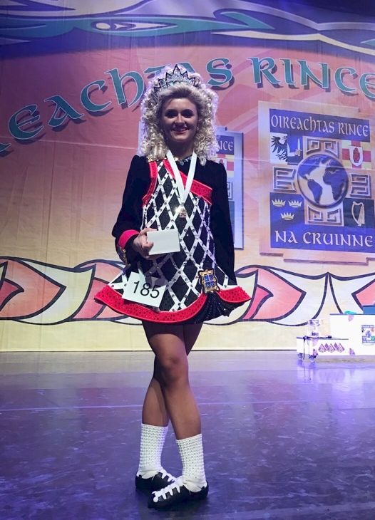 Nora Ahern poses on stage  with her award at an Irish dancing competition.