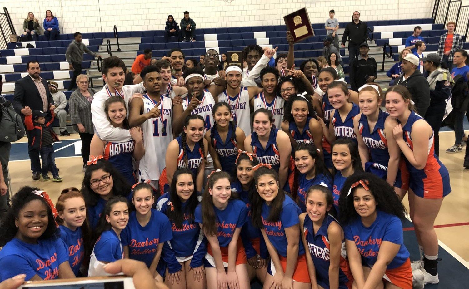 The Danbury boys' basketball team celebrates its FCIAC championship win over Trumbull with fans and cheerleaders.