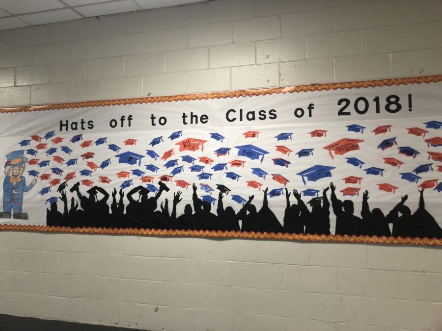 Students post their college decisions on graduation hats located on a bulletin board outside of the cafeteria.