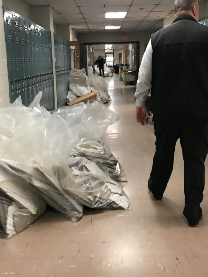 Principal Dan Donovan inspects C3 on Wednesday, Jan. 23, as crews remove damaged ceiling tiles and bag them up for disposal. 