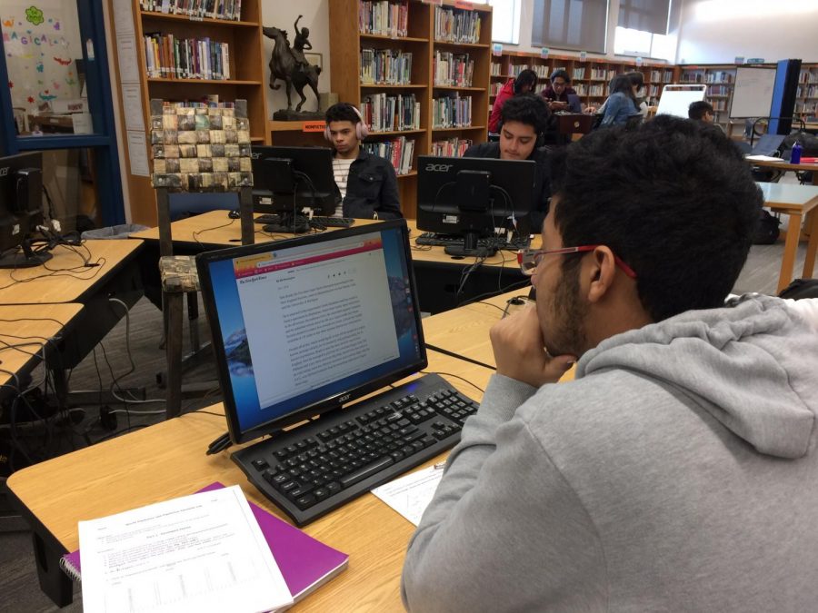 Senior Angel Almonte in the LLC reads a New York Times article about Patriots quarterback Tom Brady becoming New Englands favorite adopted son.