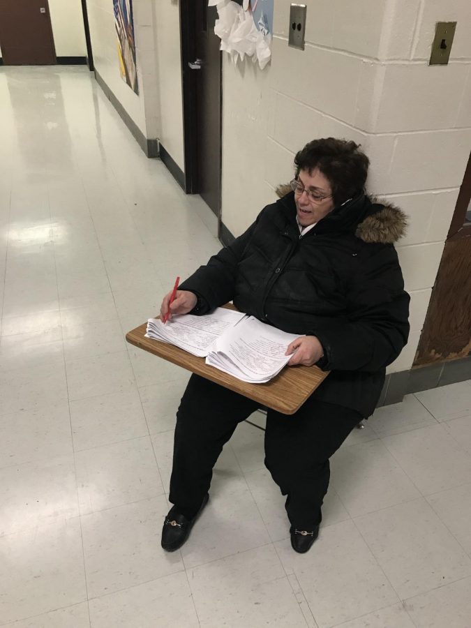 Teacher Pat Villella tries to stay warm Friday, Feb. 1, while on hallway duty outside the cafeteria. In between challenging students for passes, she uses this time to grade her students World Language work.