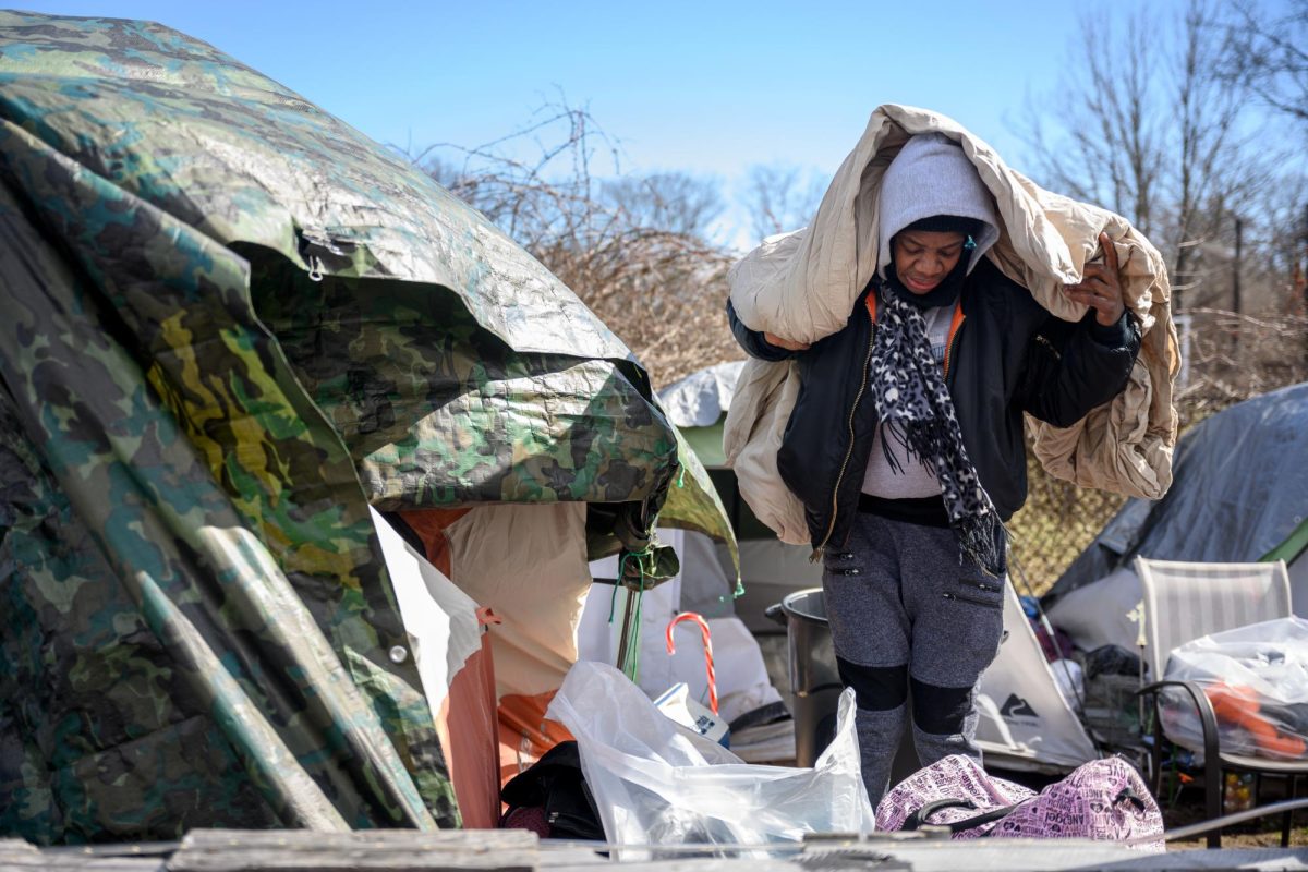 Jaquedah Williams sorts through belongings to throw away as she faces an eviction order from the city to leave the camp where she and several other people have been living.